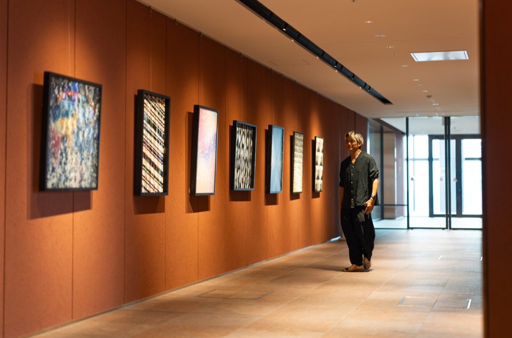 八木ジンが自身の個展に並ぶ作品を見ている写真